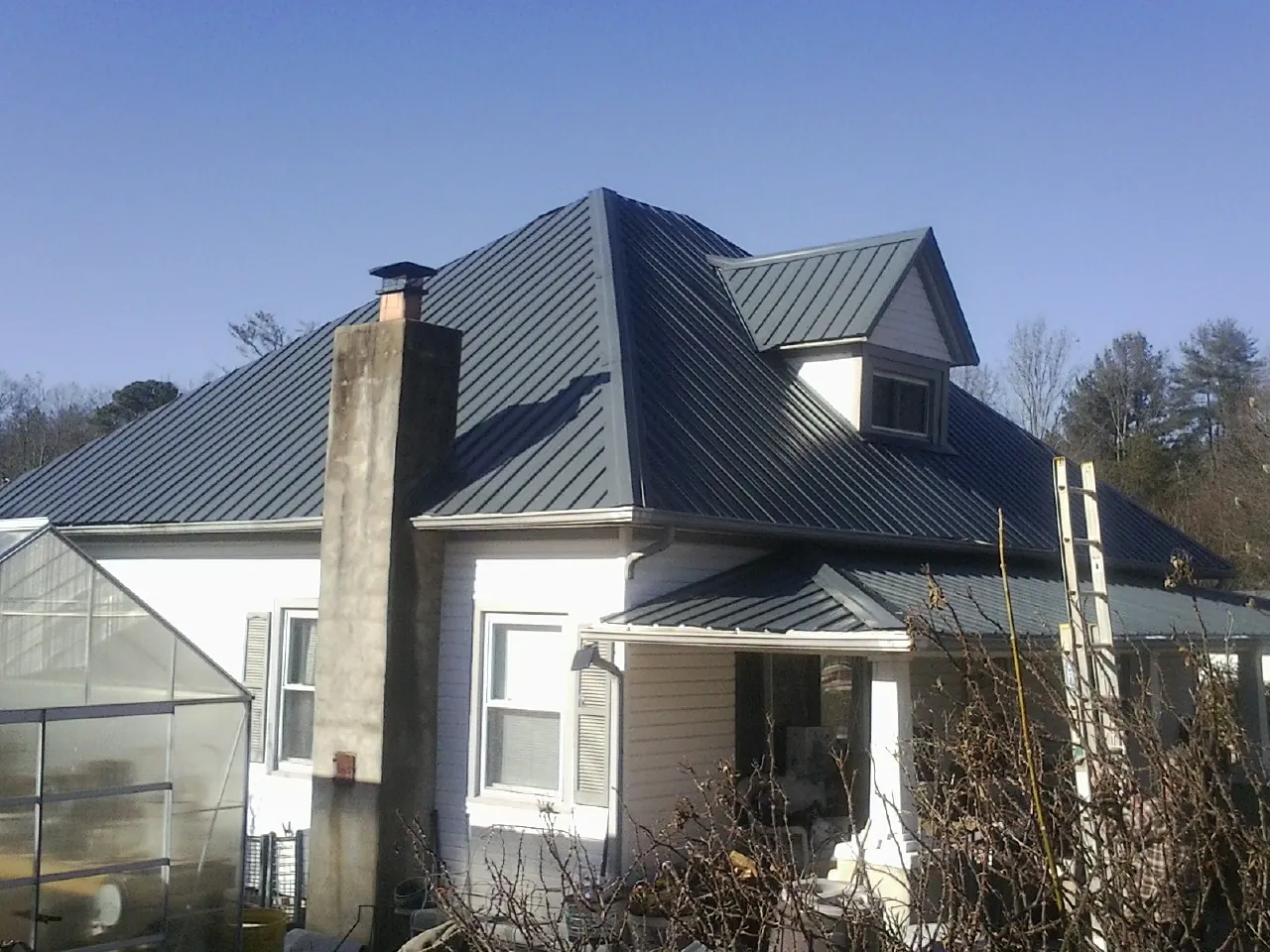 Dark blue standing seam metal roof on a white farmhouse with dormer — Slate & Tile Roof Repair by Roofing Brothers in Senecaville