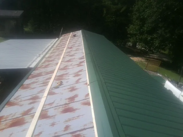 Old rusted panels beside newly installed green metal roofing — Wind Damage Roof Repair by Roofing Brothers in Senecaville