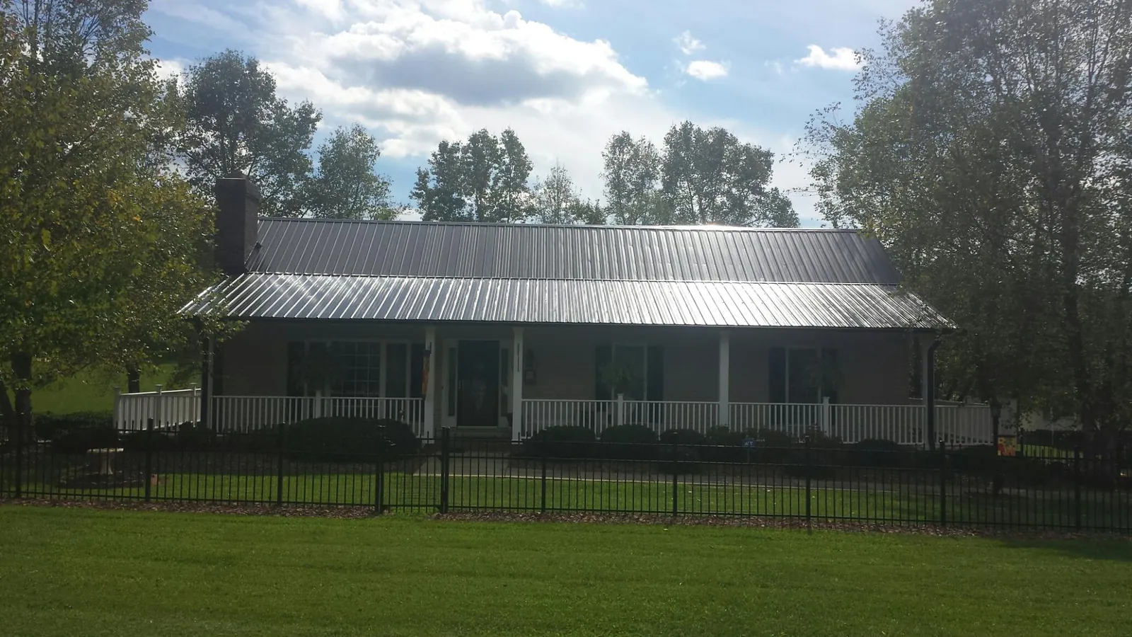 Gray metal roof on a brick ranch with a full width front porch — Gutter Guard Installation work by our crew in Senecaville