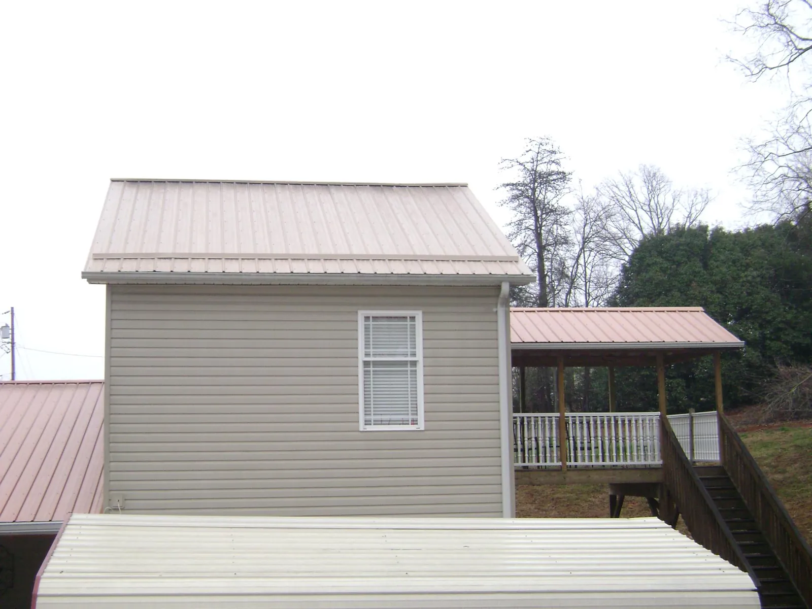 Tan metal roofs on a two story addition and attached porch, from a Roof Replacement job in Senecaville