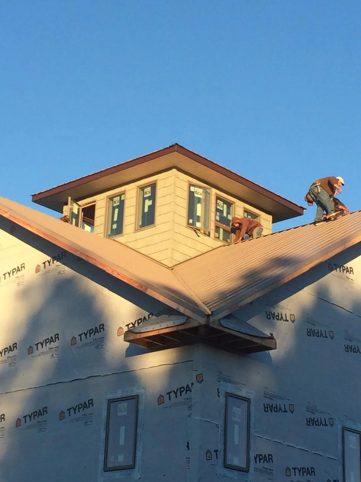 Roofers working around a rooftop cupola on a new metal roof at sunset — Roof Waterproofing in Senecaville by Roofing Brothers
